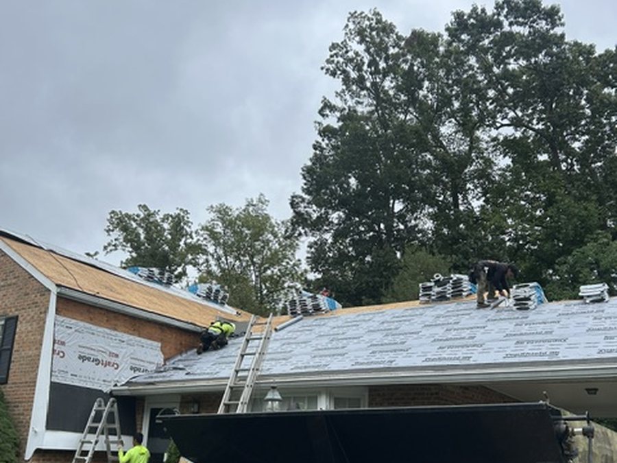 D&K Contractors crew installing underlayment and staging shingle bundles on a Howard County roof